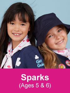 Two Girl Guides aged 5 to 6 smiling and linking arms
