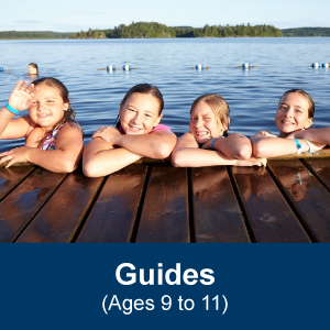 Five Girl Guides aged 9 to 11 posing on a dock at the side of a lake during a camping trip