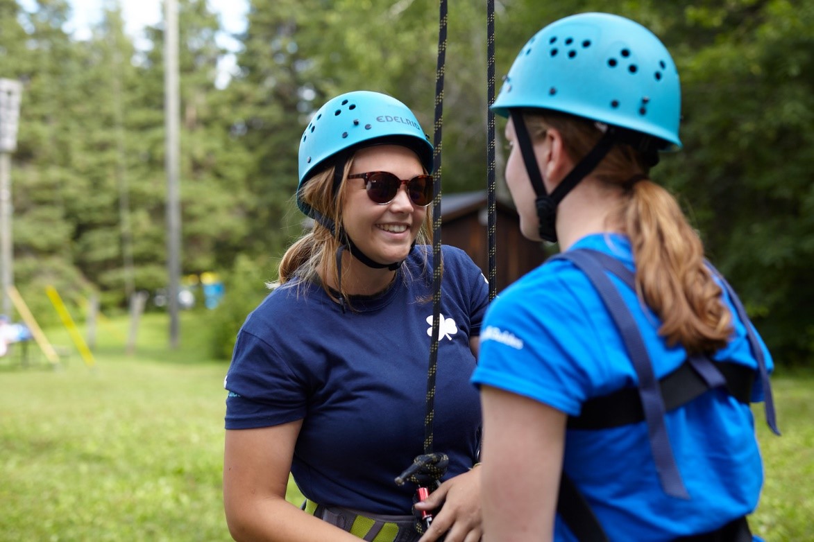 Two Girl Guides aged 15 to 17 wearing helmets and wearing harnesses