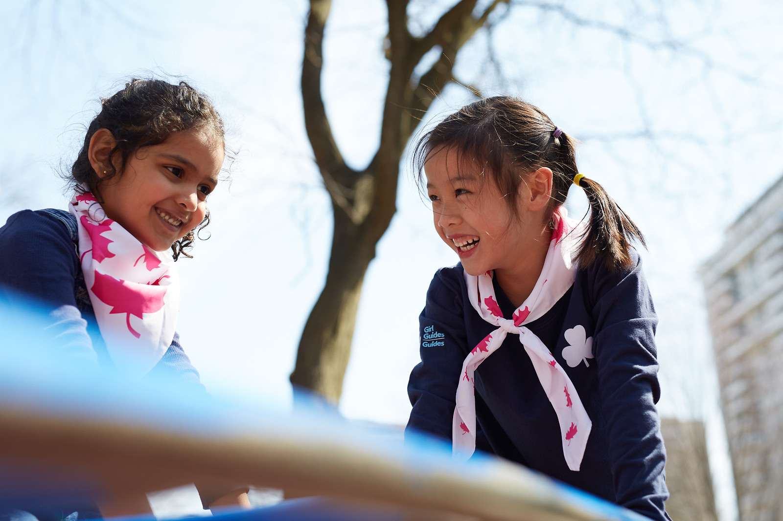 Two Girl Guides aged 5 to 6 smiling and playing together outside